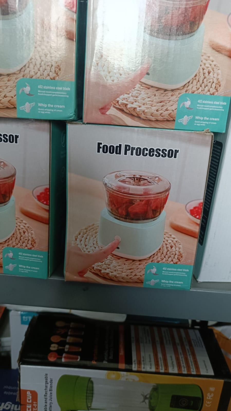 Multifunctional food processor in light blue with clear container chopping red ingredients on a woven placemat