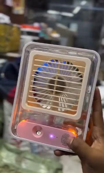 Livingdot portable rechargeable misting fan with clear casing held in hand showing front grill and control button