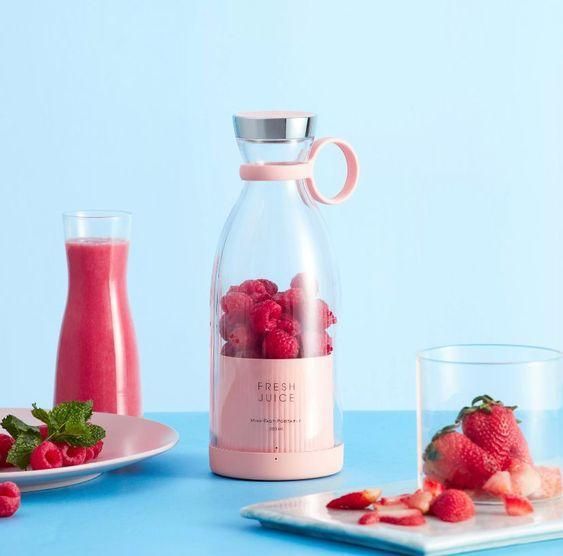 Livingdot portable mini juice blender in pink with fresh raspberries and strawberries on a blue background